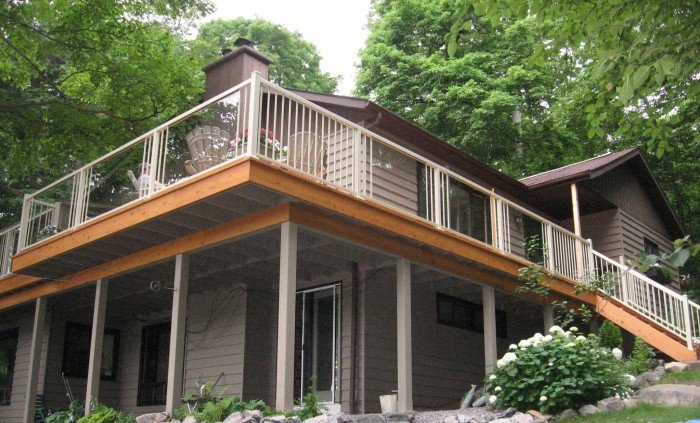 Raised lakeside deck with warm wood surface and slim cream aluminum railing