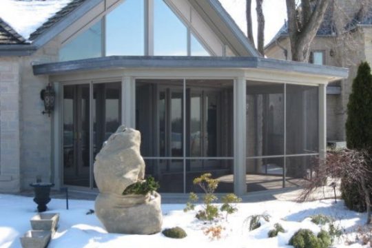 Stone-clad Vista screen room beside a backyard pool with a rooftop deck above