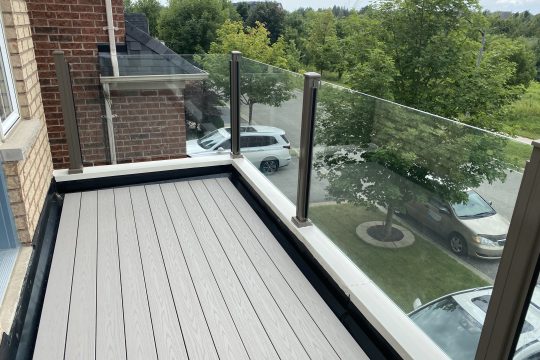 Greige composite balcony decking with clean board lines and glass railing