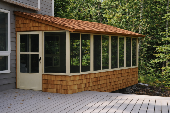 Cedar-shingled sunroom in the forest enclosed with Vista sliding windows and a screen door
