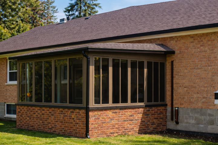 Earthstone-framed Vista sliding glass windows enclosing a sunroom on a brick home